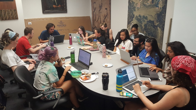 A group of people around a table with laptops working on data analysis