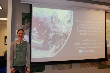 Dr. Alix Contosta stands in front of her presentation being projected on a screen